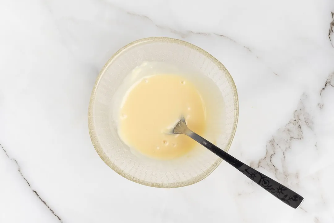 a spoon in a glass bowl of salad dressing