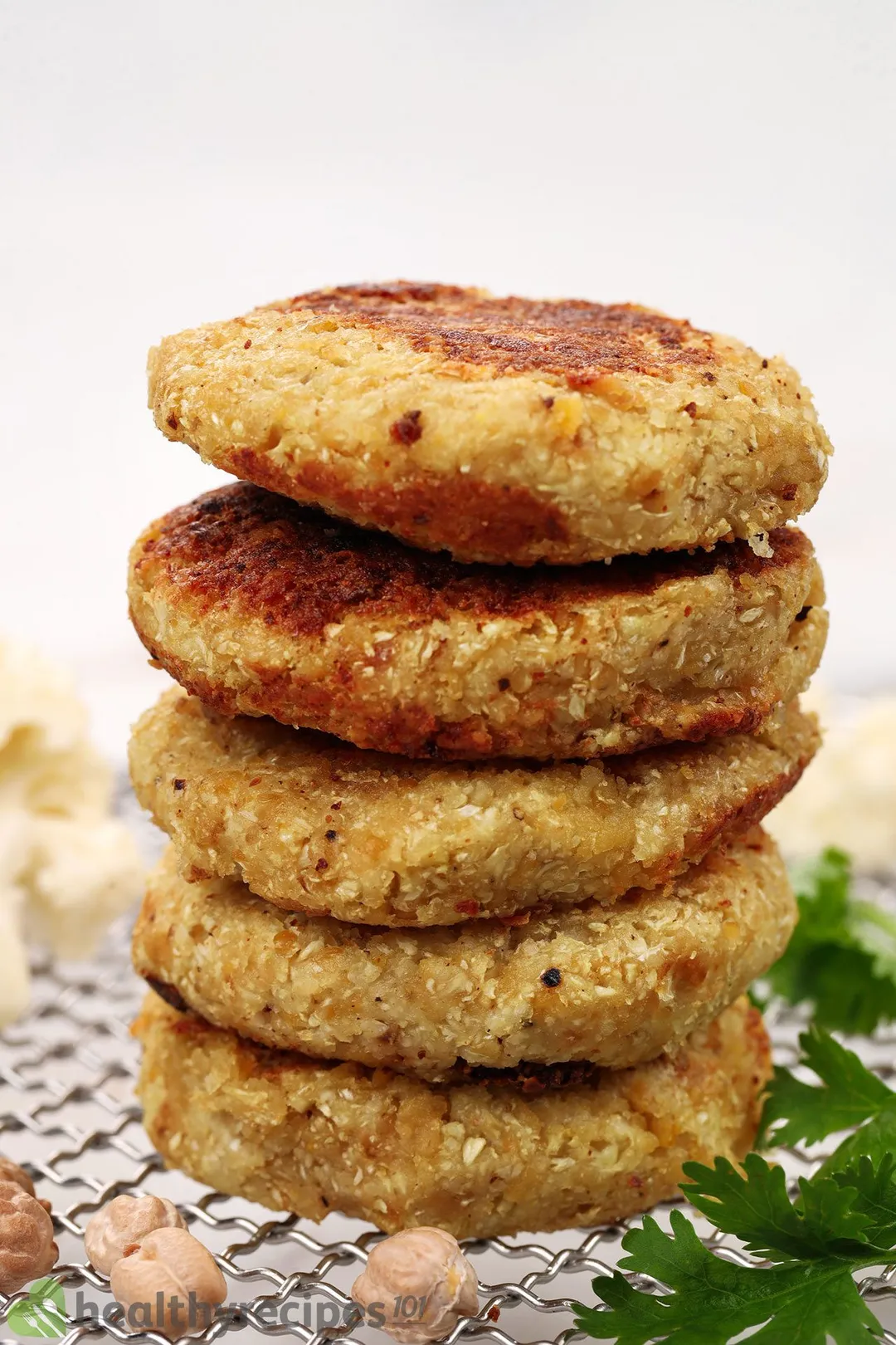 five cauliflower patties on a baking sheet