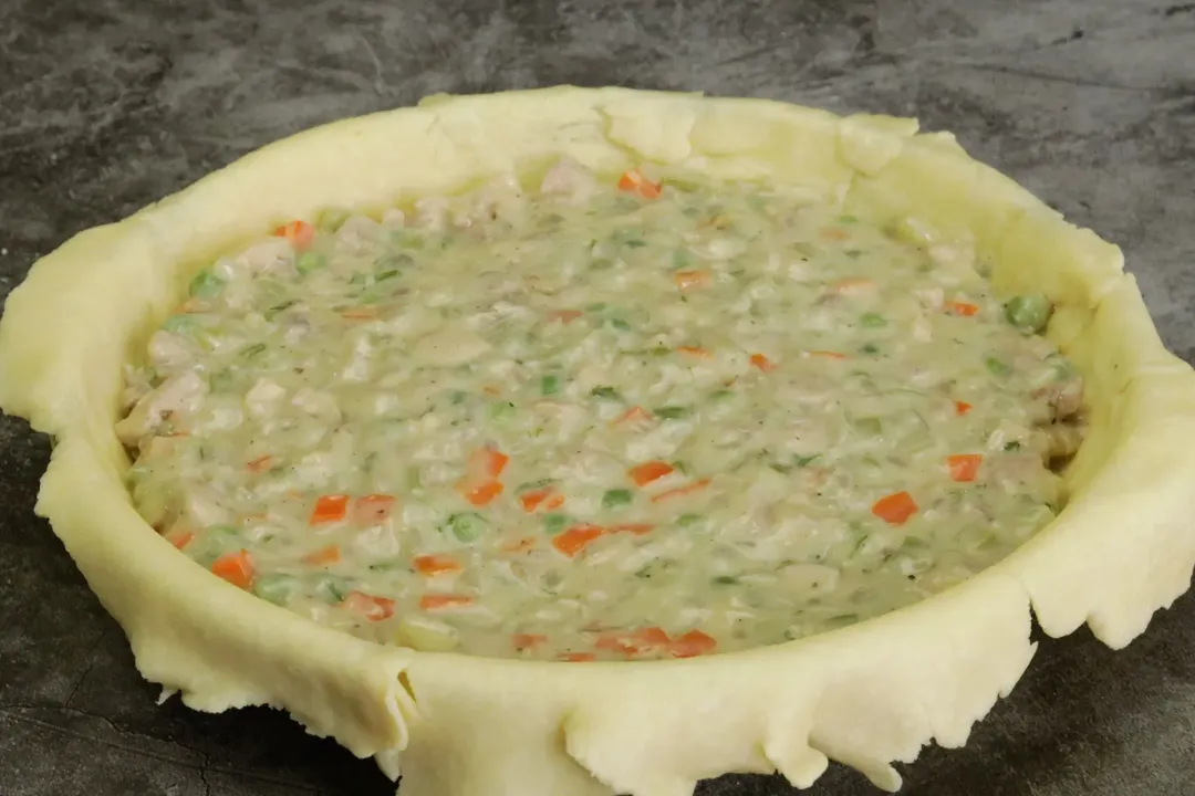 A round dish lined with pastry dough and filled with a creamy, diced vegetable soup
