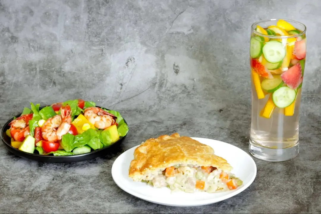 A plate of chicken pot pie, detox water, and salad