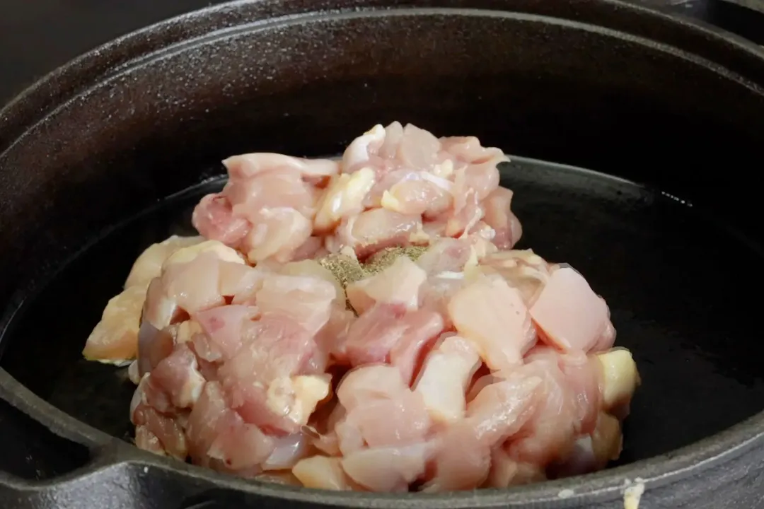 A pot cooking raw chicken pieces