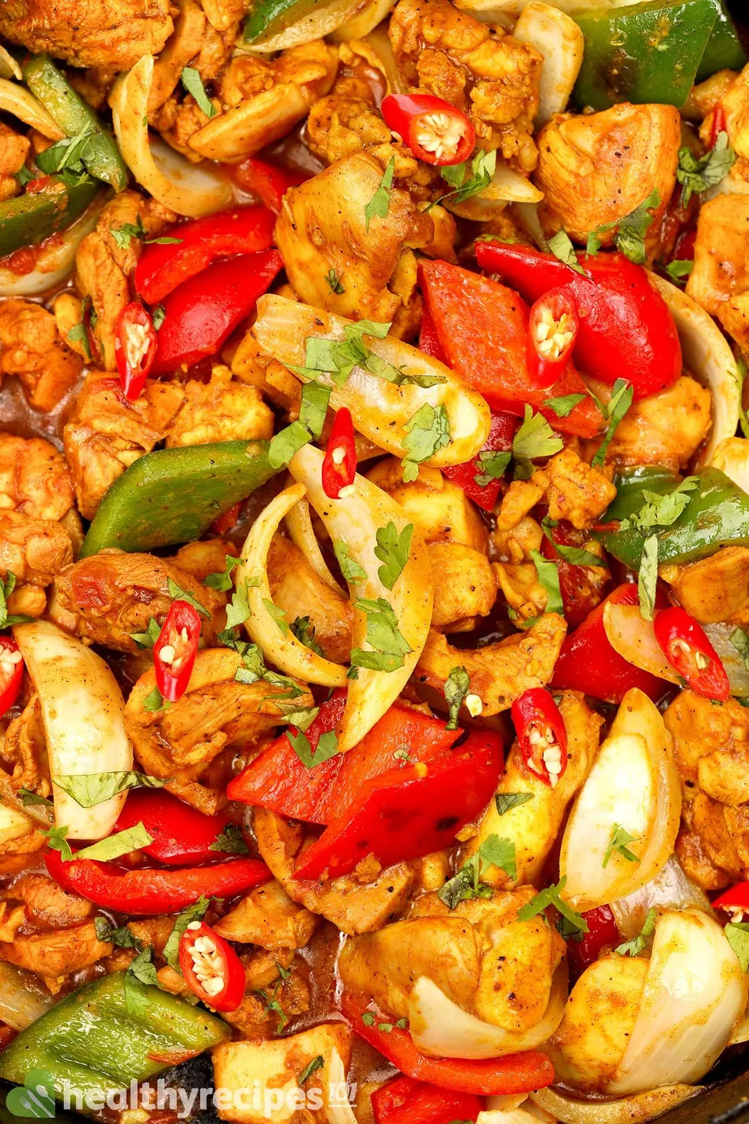 a close-up shot of cooked cubed chicken with cubed red and green pepper and onion garnished with chopped coriander