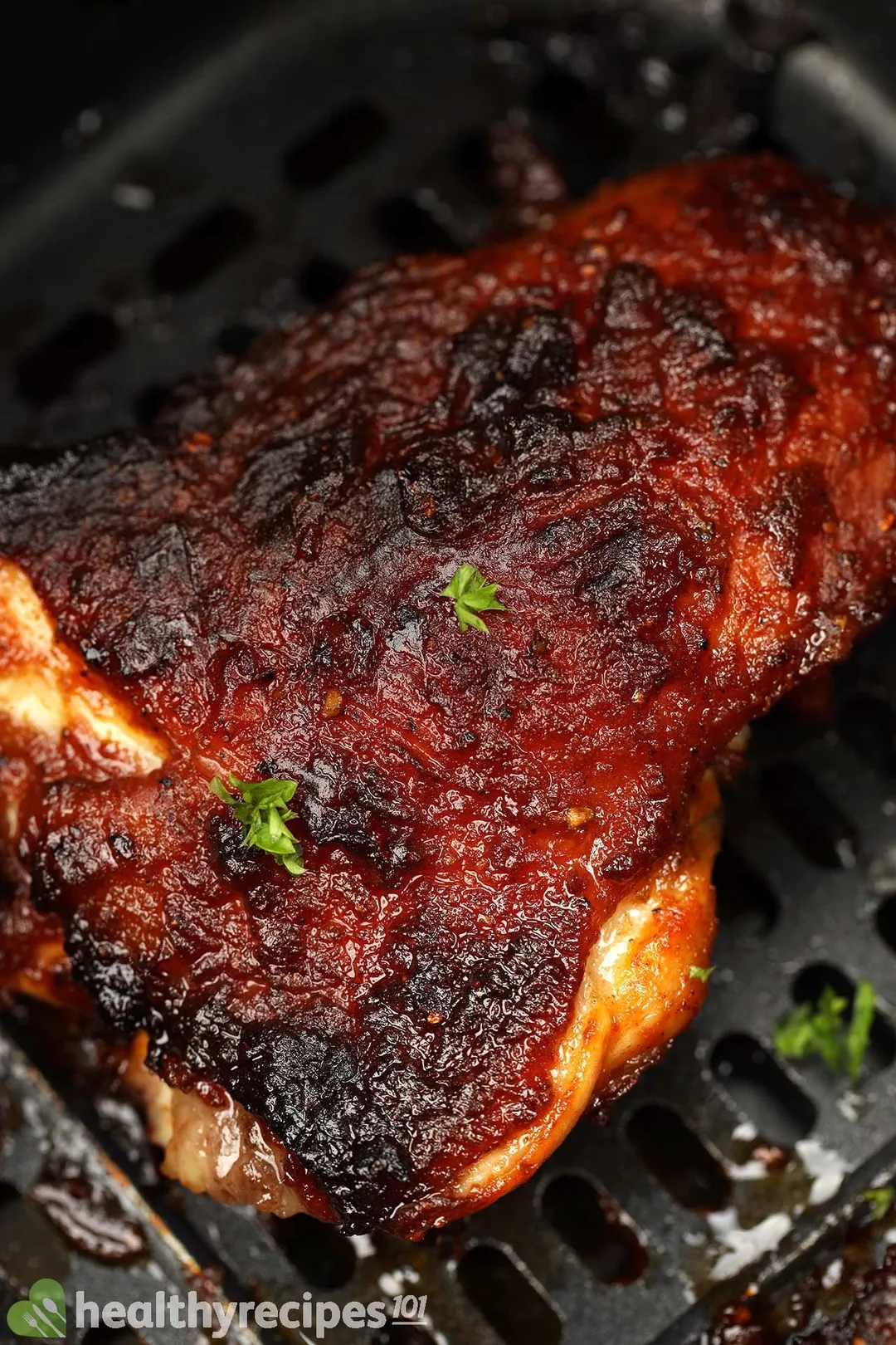 close-up shot of grilled chicken thigh on a plate with lettuce, half tomato and potato wedge decorated with fork and knife