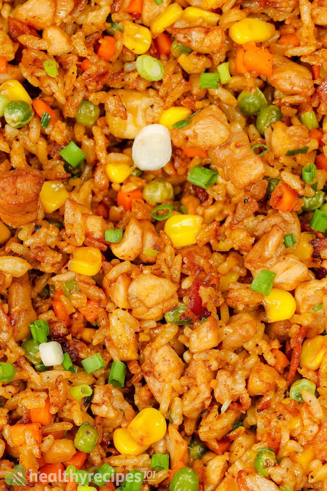 close-up shot of cooked cubed chicken with rice and corn, green bean garnished with chopped scallion