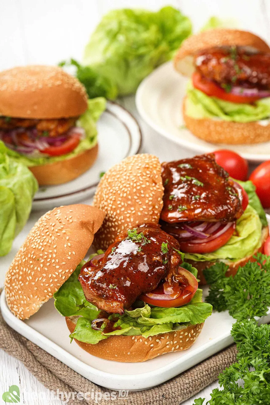 Two Buffalo chicken sandwiches on a white plate with two more in the background