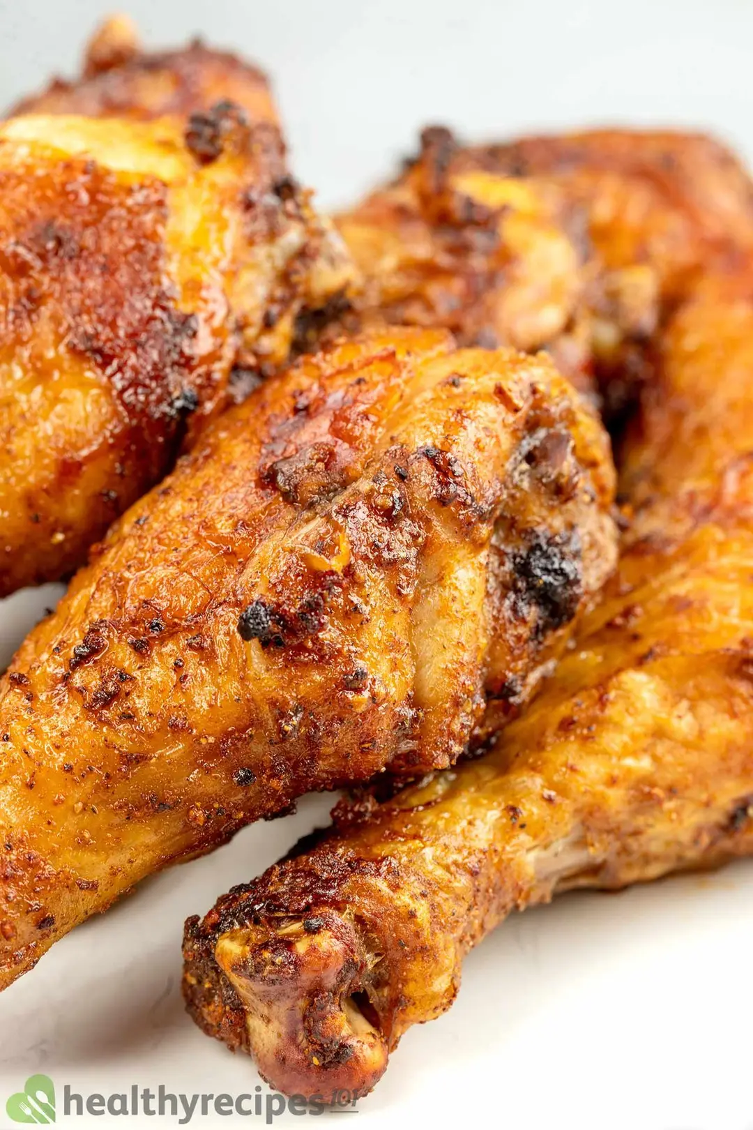 close-up shot of four cooked chicken drumsticks on a white plate