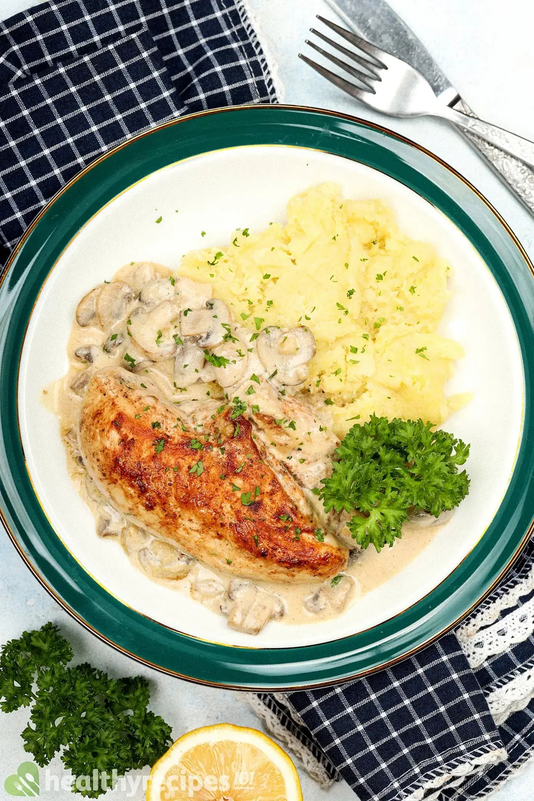 a plate of cooked chicken breast with mushroom and mashed potatoes, garnished with parsley and chopped parsley
