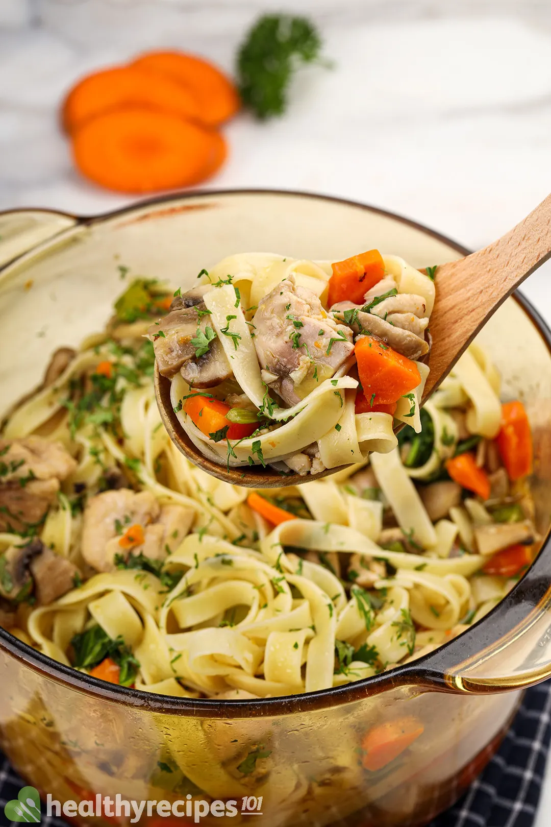 a wooden spoon full of chicken and noodle on top of a chicken noodle soup