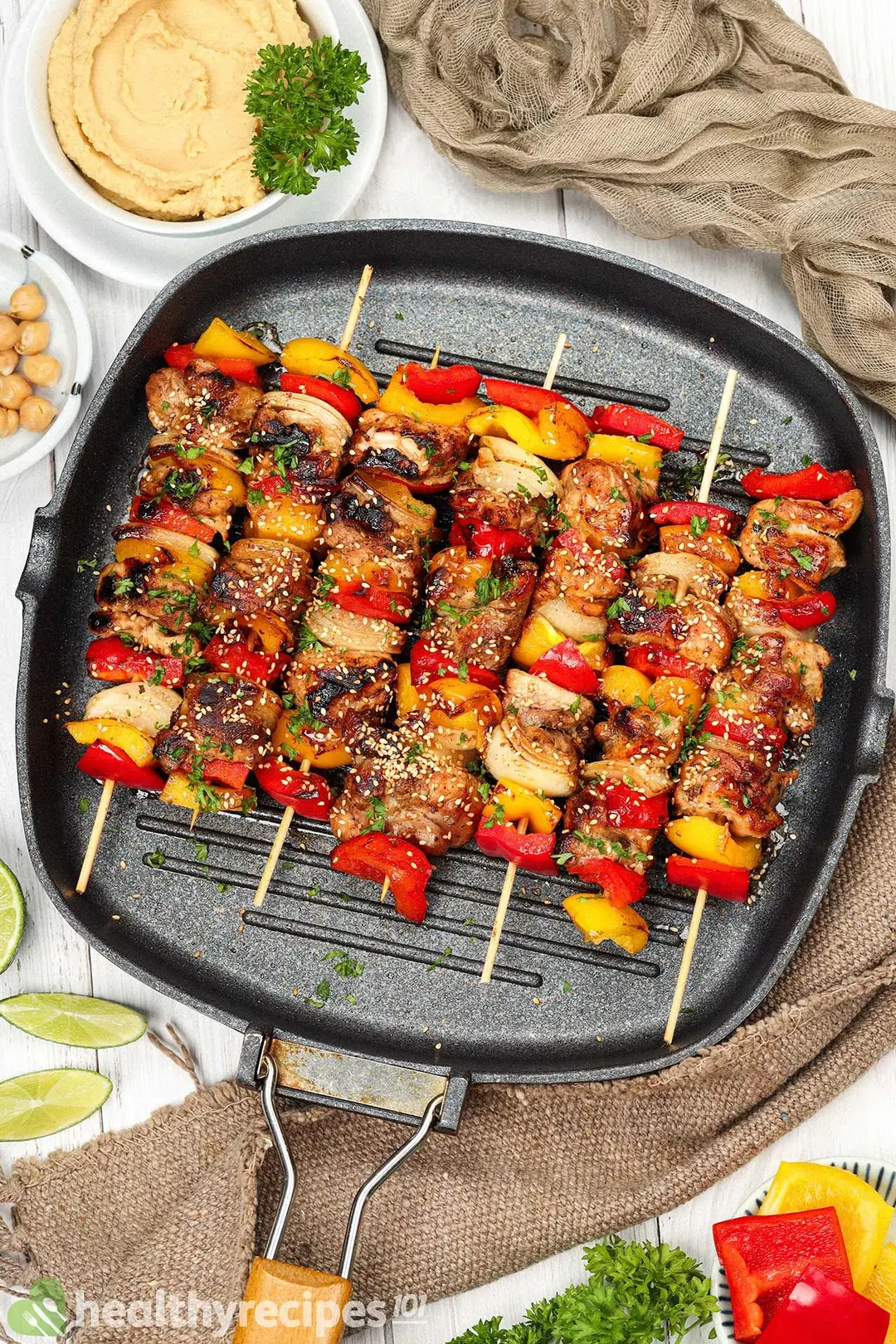Chicken skewers in a cast iron skillet alongside chickpea puree