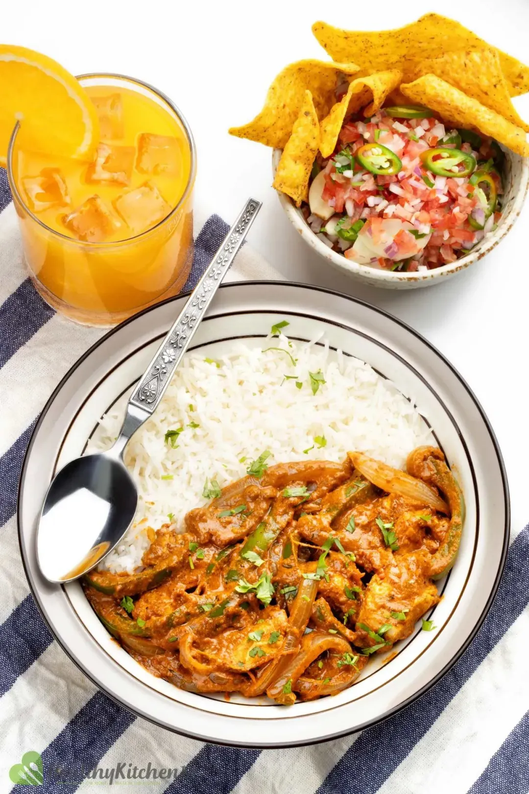 A meal consisting of Chicken Tikka Masala and rice, pico de gallo, and a glass of orange juice