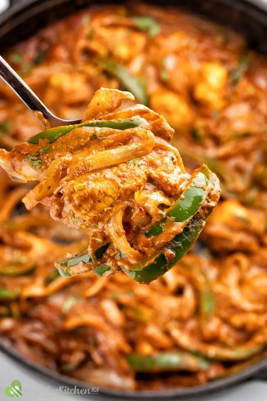 A fork picking up vegetable matchsticks covered in a Tikka Masala sauce