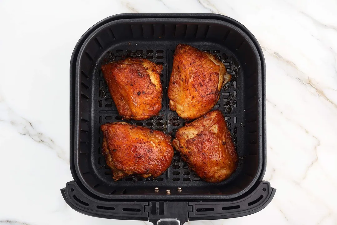 four chicken thighs in an air fryer basket