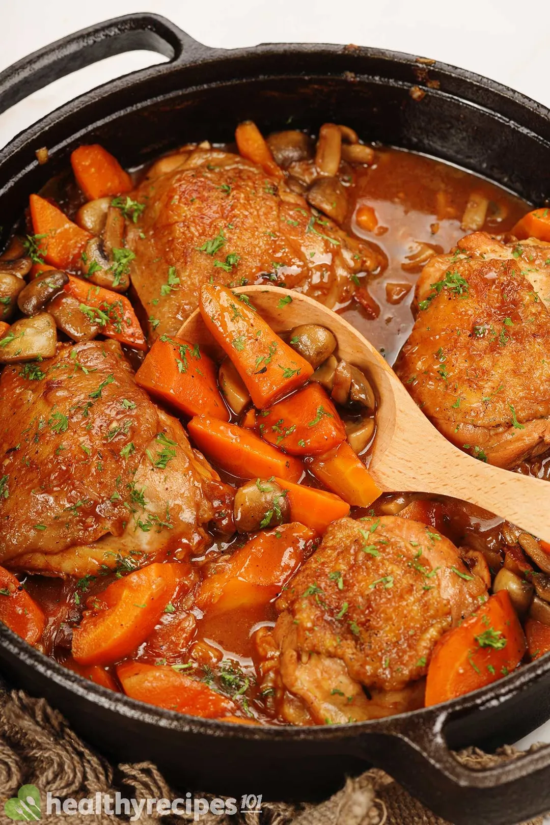 cooked chicken thighs and carrot, mushroom with sauce in a cast iron skillet