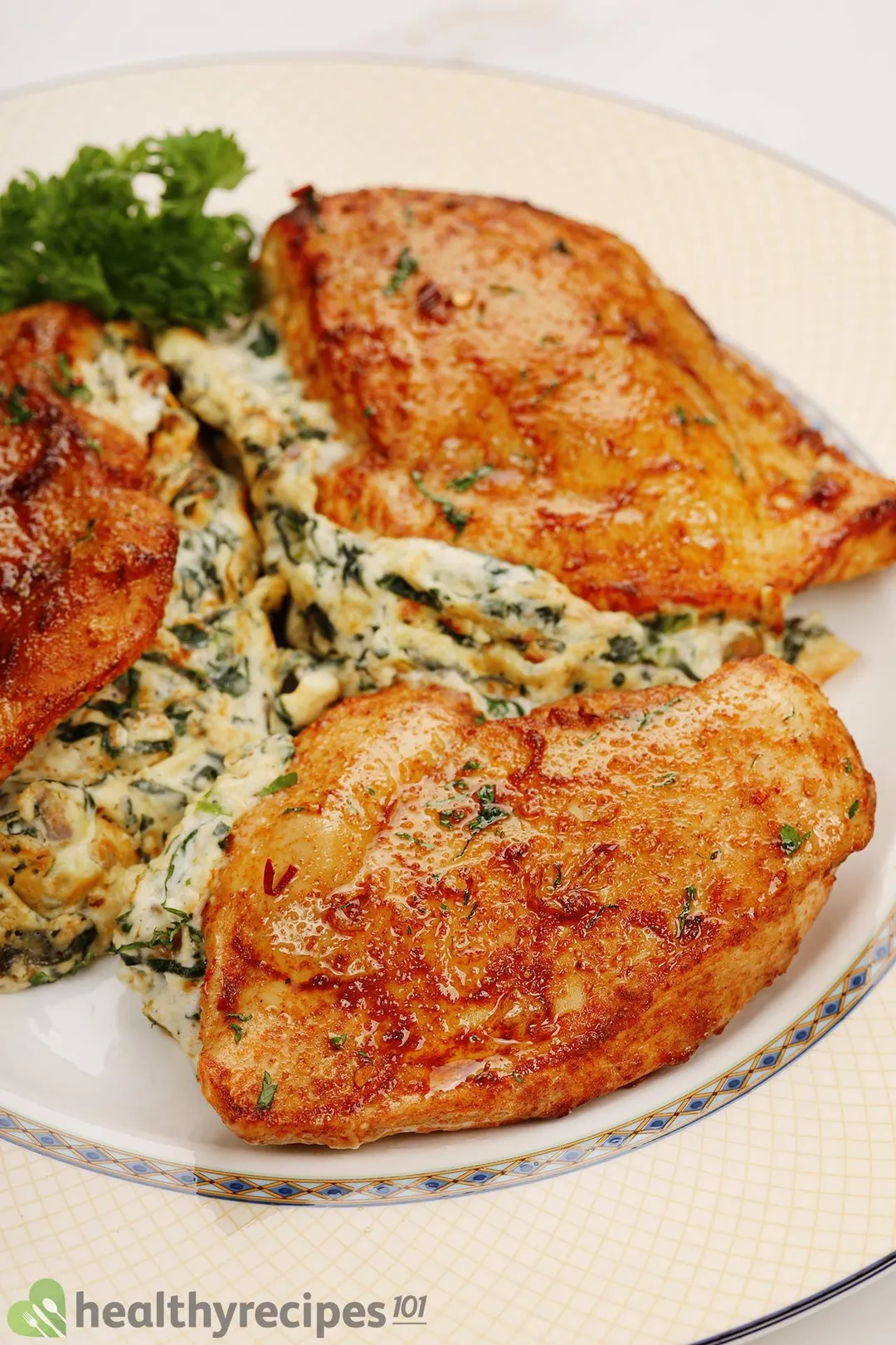 three cooked stuffed chicken breasts on a plate decorated with parsley