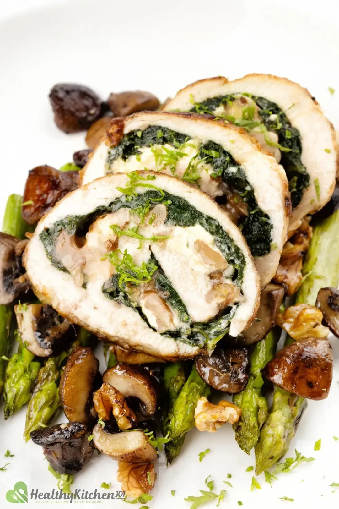 A close up shot of Stuffed Chicken Breast laid on a bed of asparagus.
