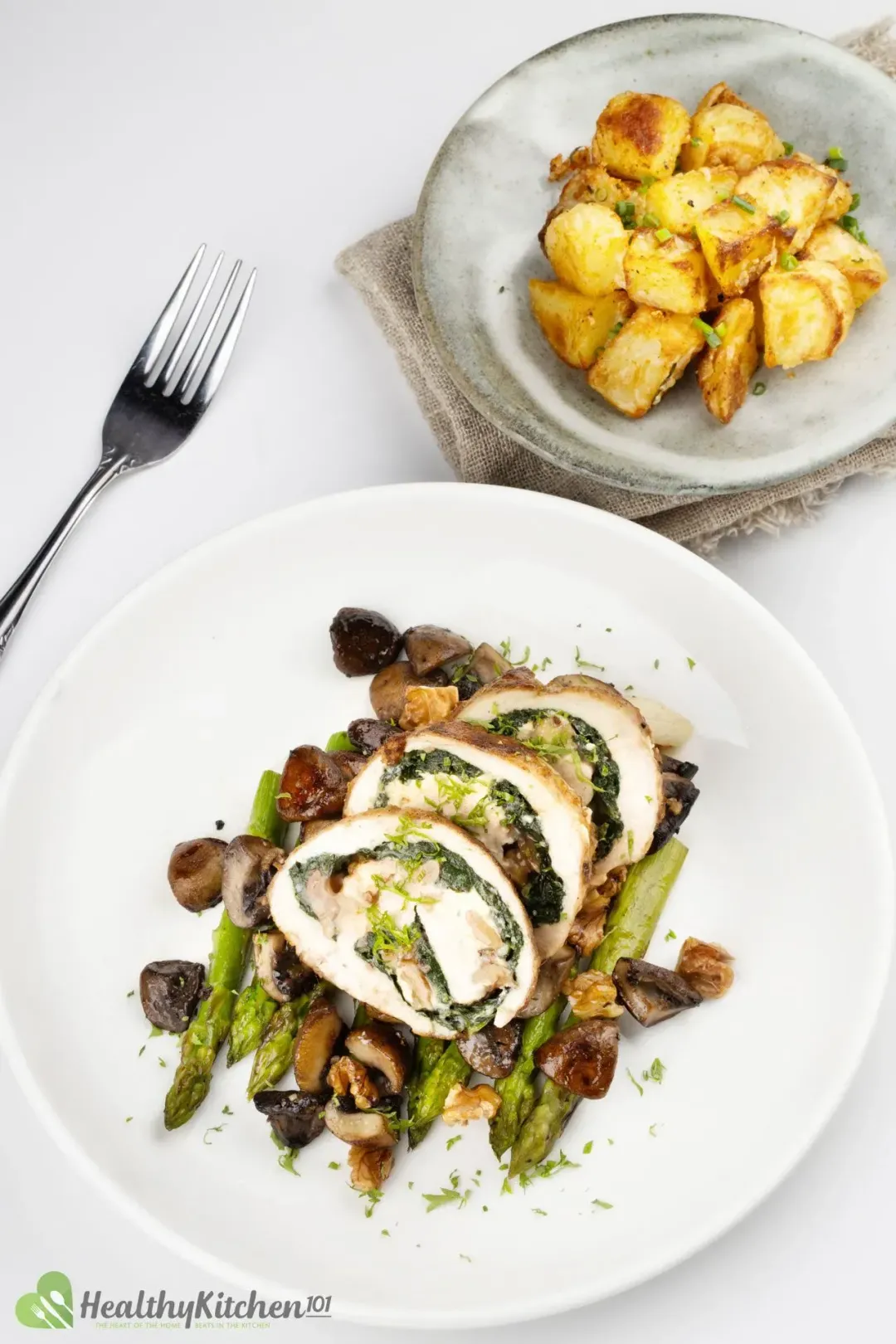 A plate of Stuffed Chicken Breast placed near a plate of potatoes.