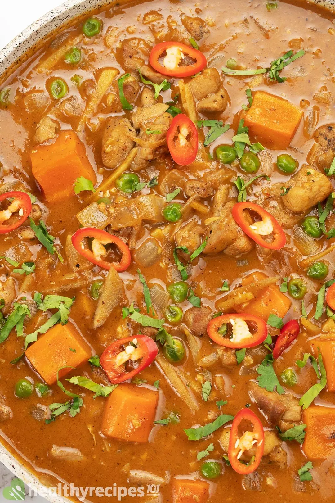 a non stick skillet of thai chicken curry garnish by pepper coriander