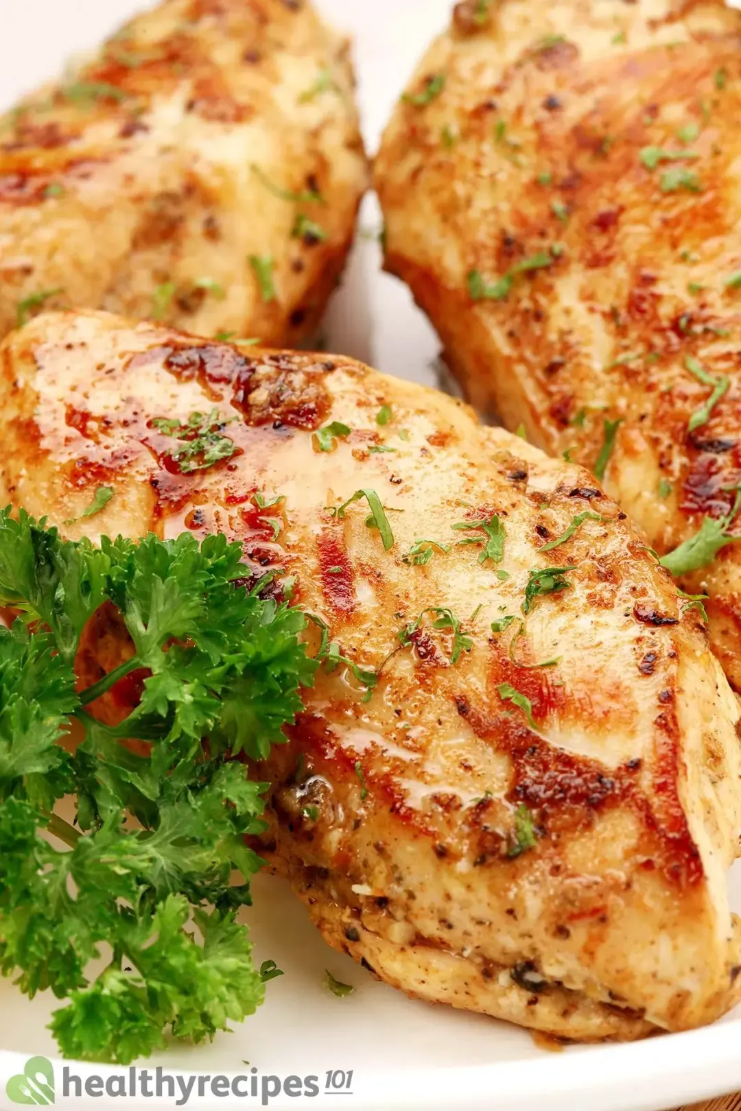three cooked chicken breasts on a plate decorated with parsley