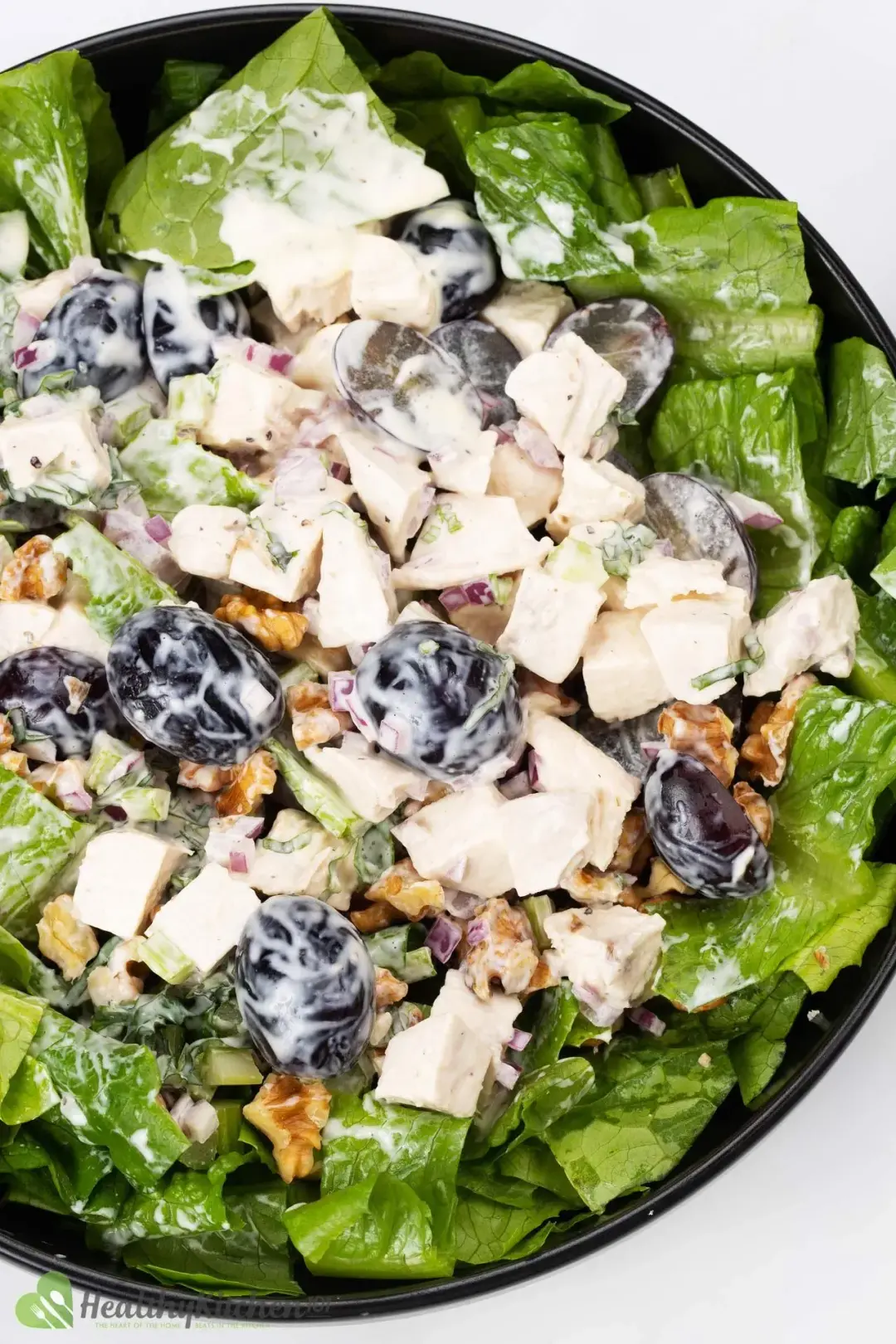 A plate full of mayonnaise-dressed waldorf salad with lettuce, grapes, walnuts, and chicken breasts
