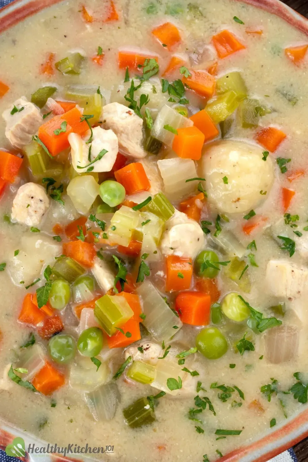 A high-angle shot of a Chicken and Dumplings soup consisting of diced vegetables and chicken dumplings.