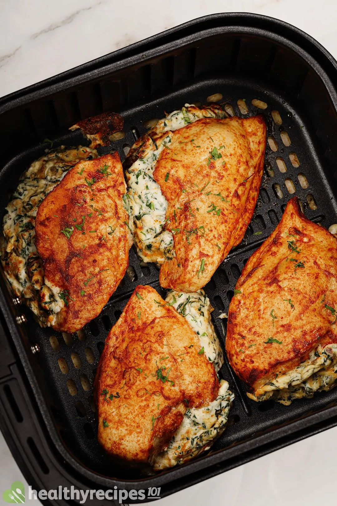four cooked chicken breasts in air fryer basket