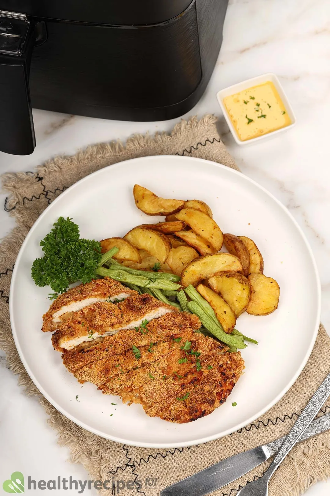 a plate of cooked chicken breast next to an air fryer