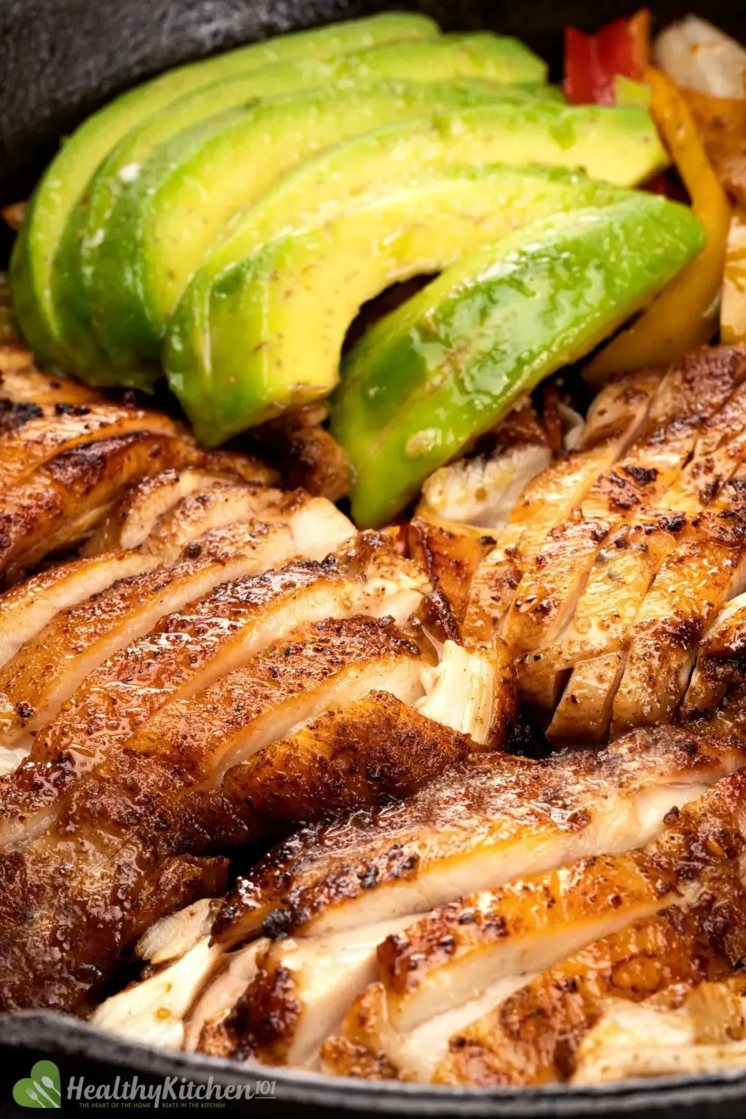A close up shot of sliced cooked chicken and avocado slices