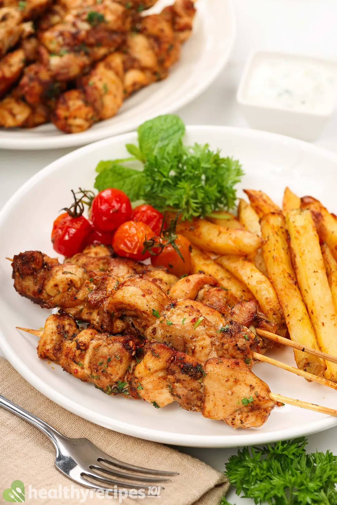 cooked chicken souvlaki on a plate with potato and tomato