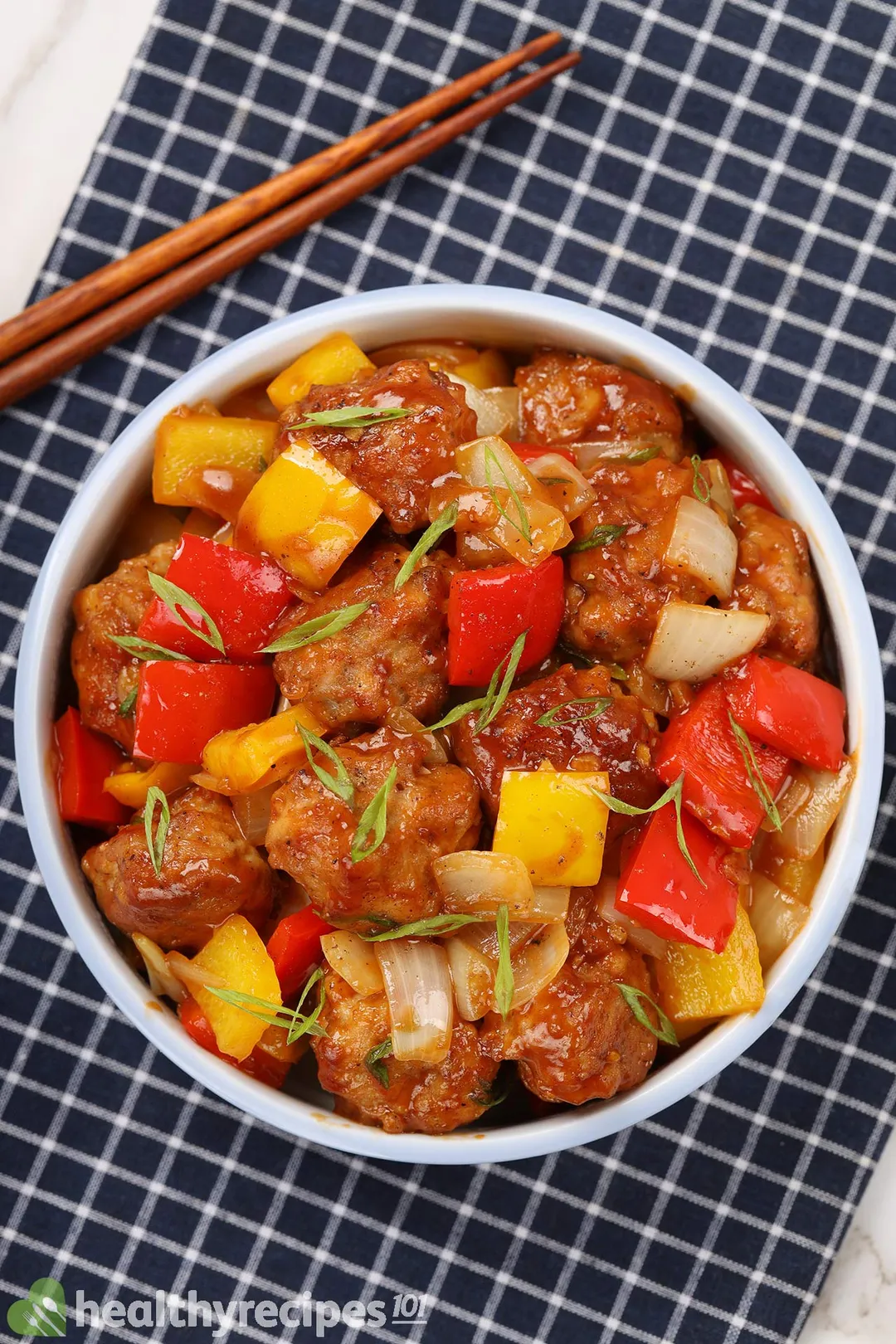 a bowl of cooked chicken with red - yellow bell pepper