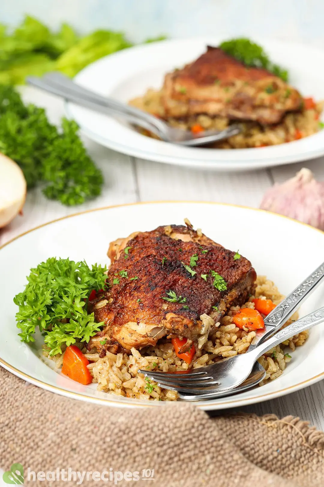 Two plates of chicken rice decorated with spoon and fork
