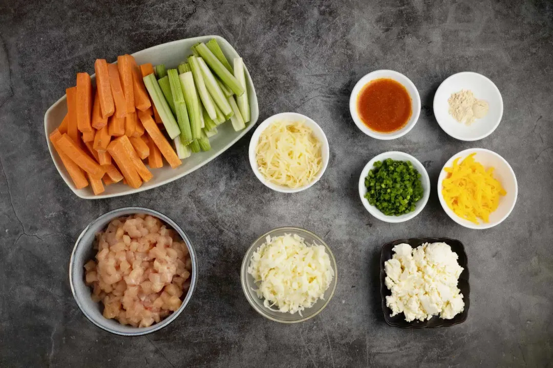 Ingredients for Buffalo Chicken Dip, including carrot sticks, celery sticks, ground chicken, and others.