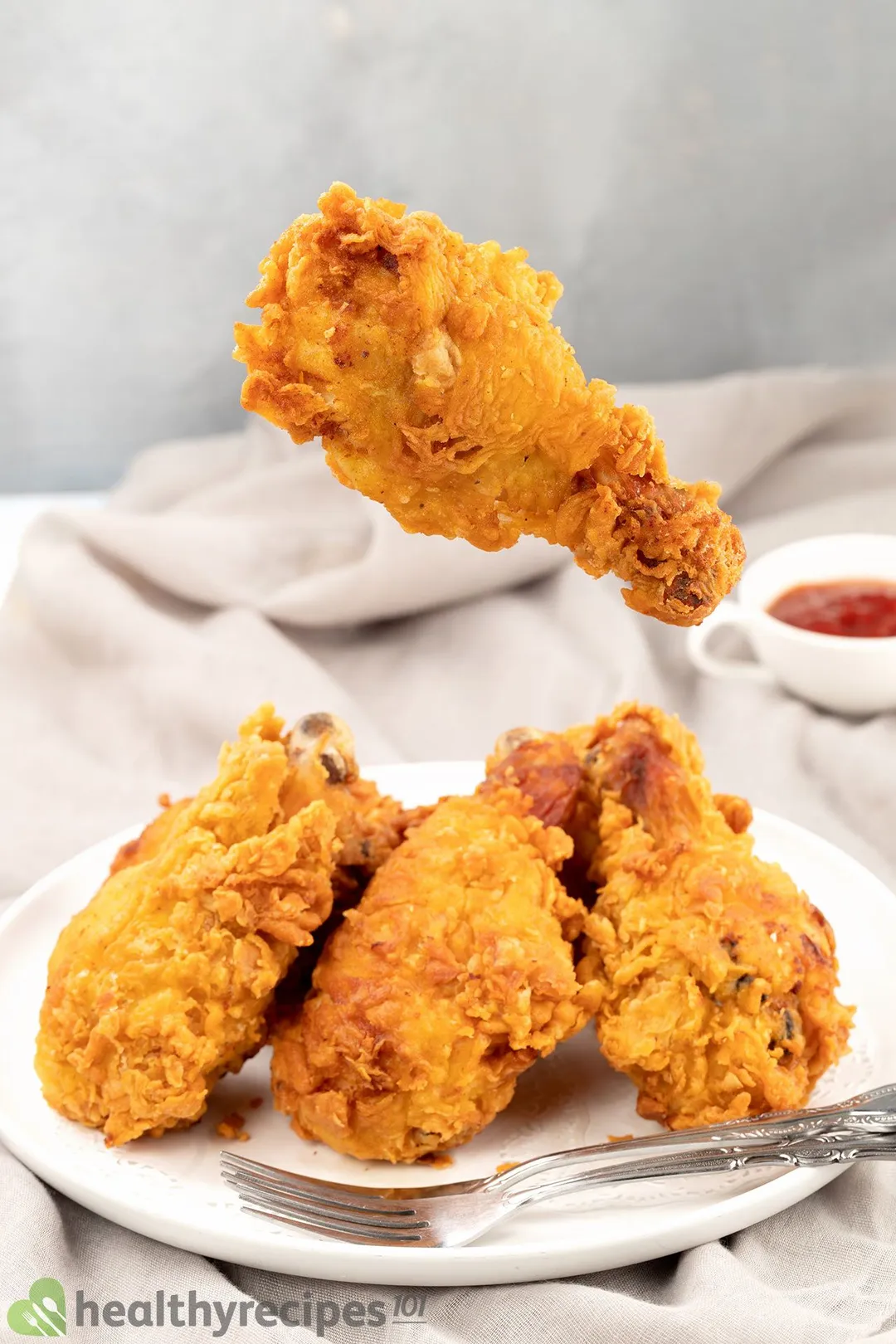 a broasted drumstick on top of a plate of cooked chicken drumsticks