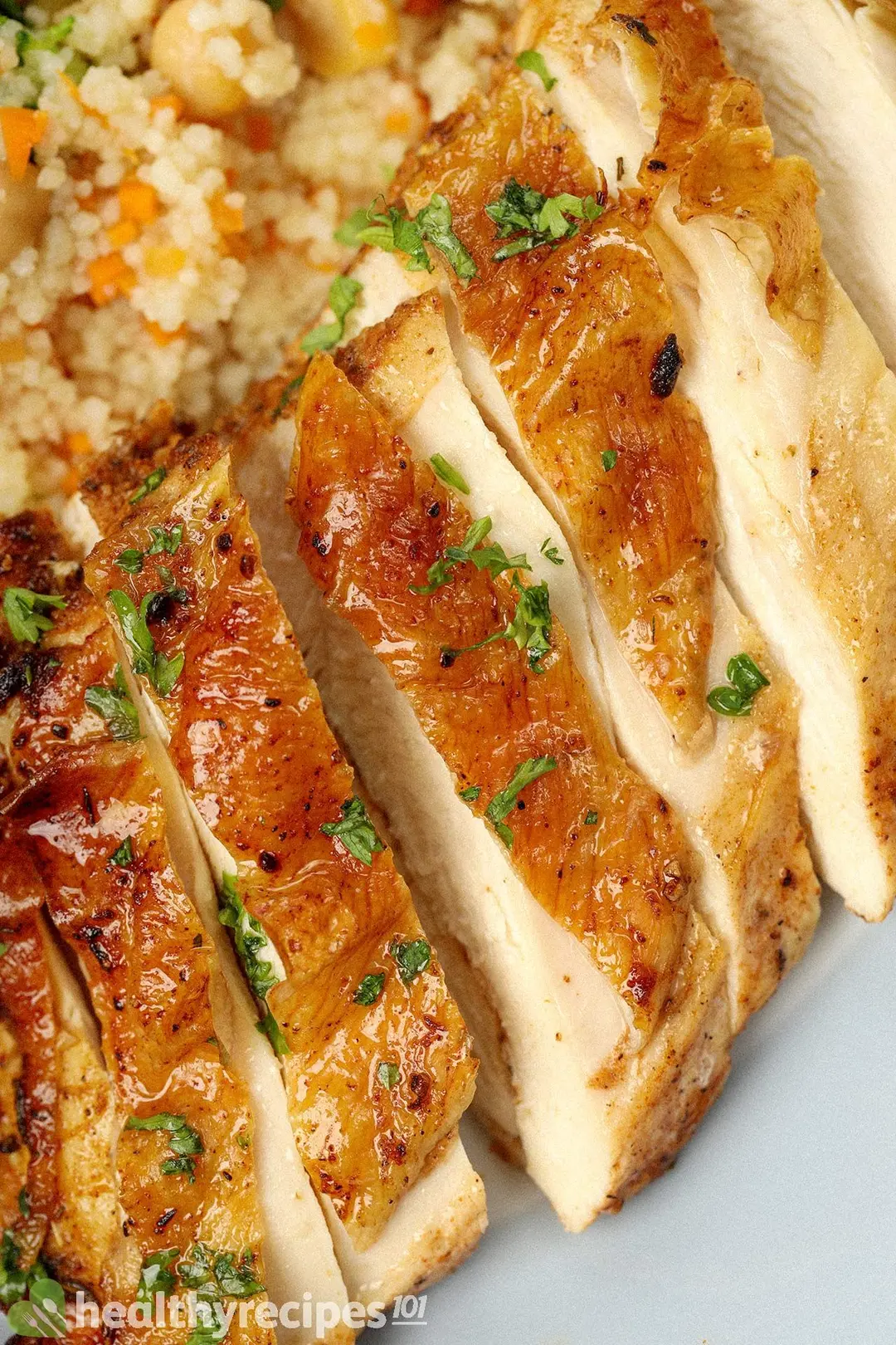 A chicken thigh cooked and browned sliced crosswise into thumb-sized pieces,  laid near cooked couscous