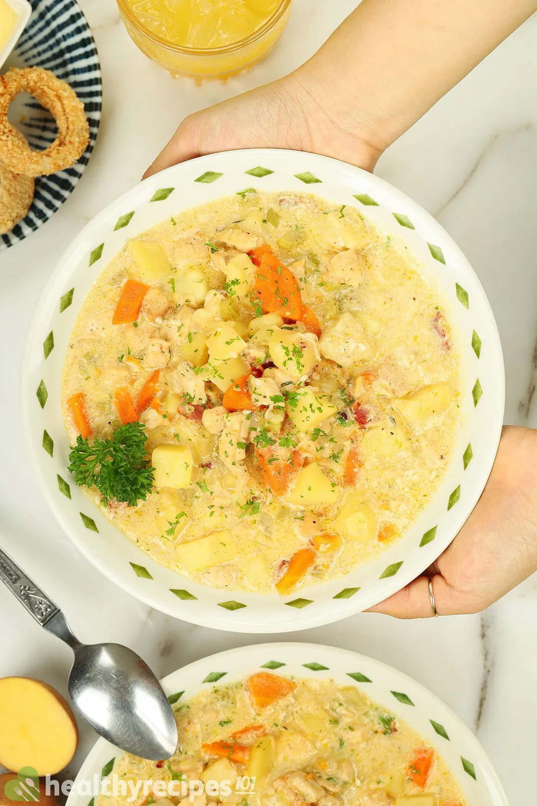 top view of two hands hold a bowl of cooked chicken potato soup