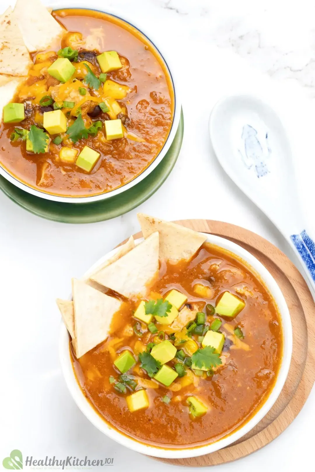 two bowls of chicken tortilla soup topped with mini zucchini cubes and tortilla chips