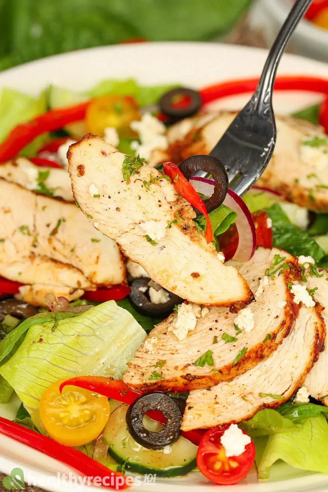 A fork piercing into a slice of cooked chicken breast.