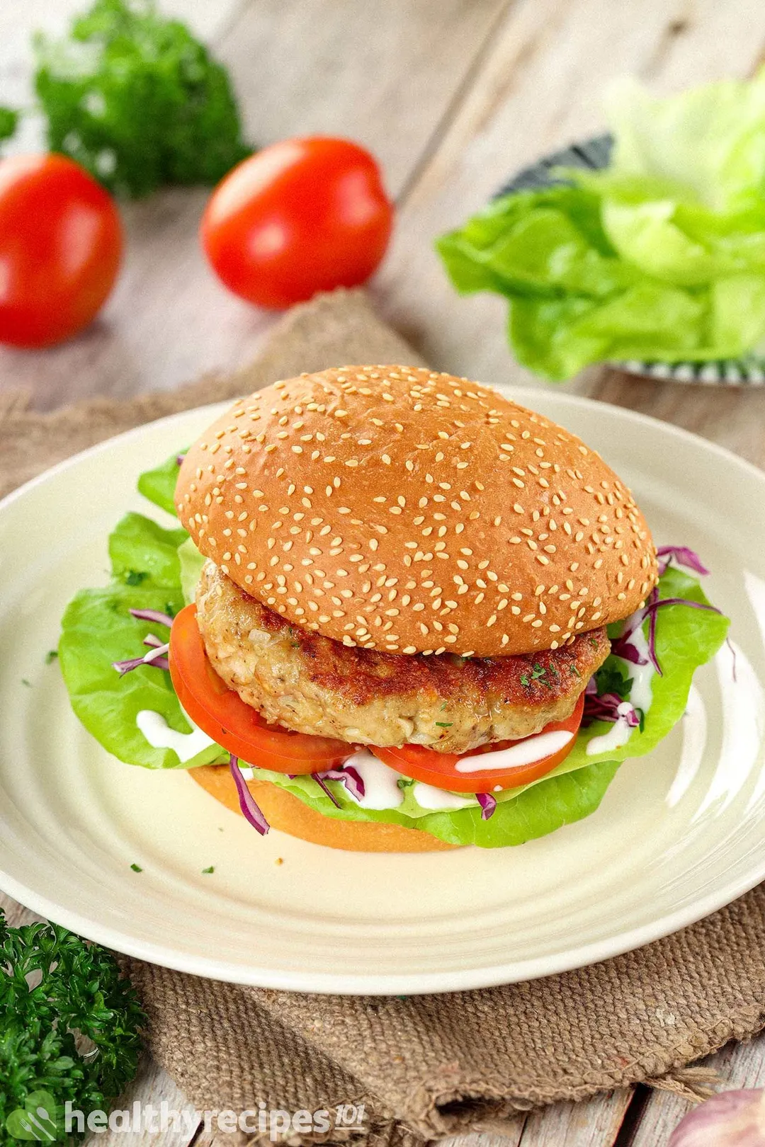 A round plate holding a hamburger placed on top of a brown fabric