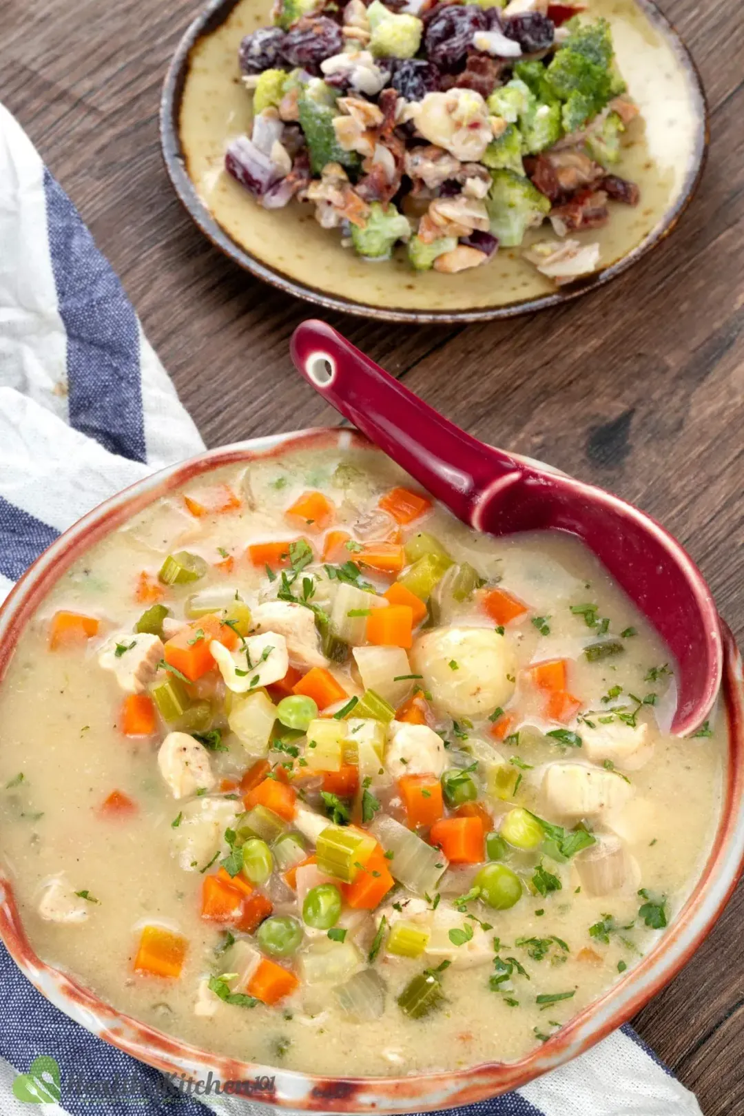 A bowl of Chicken And Dumplings placed next to a dish of sauteed vegetables