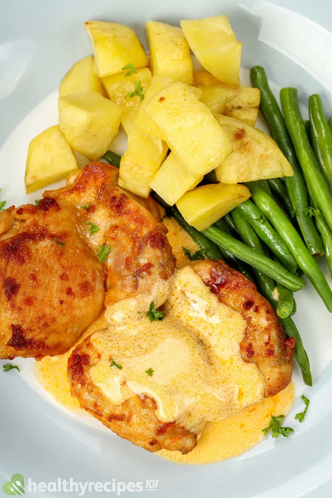 top view of a plate of cooked chicken thighs potato cubed, green bean