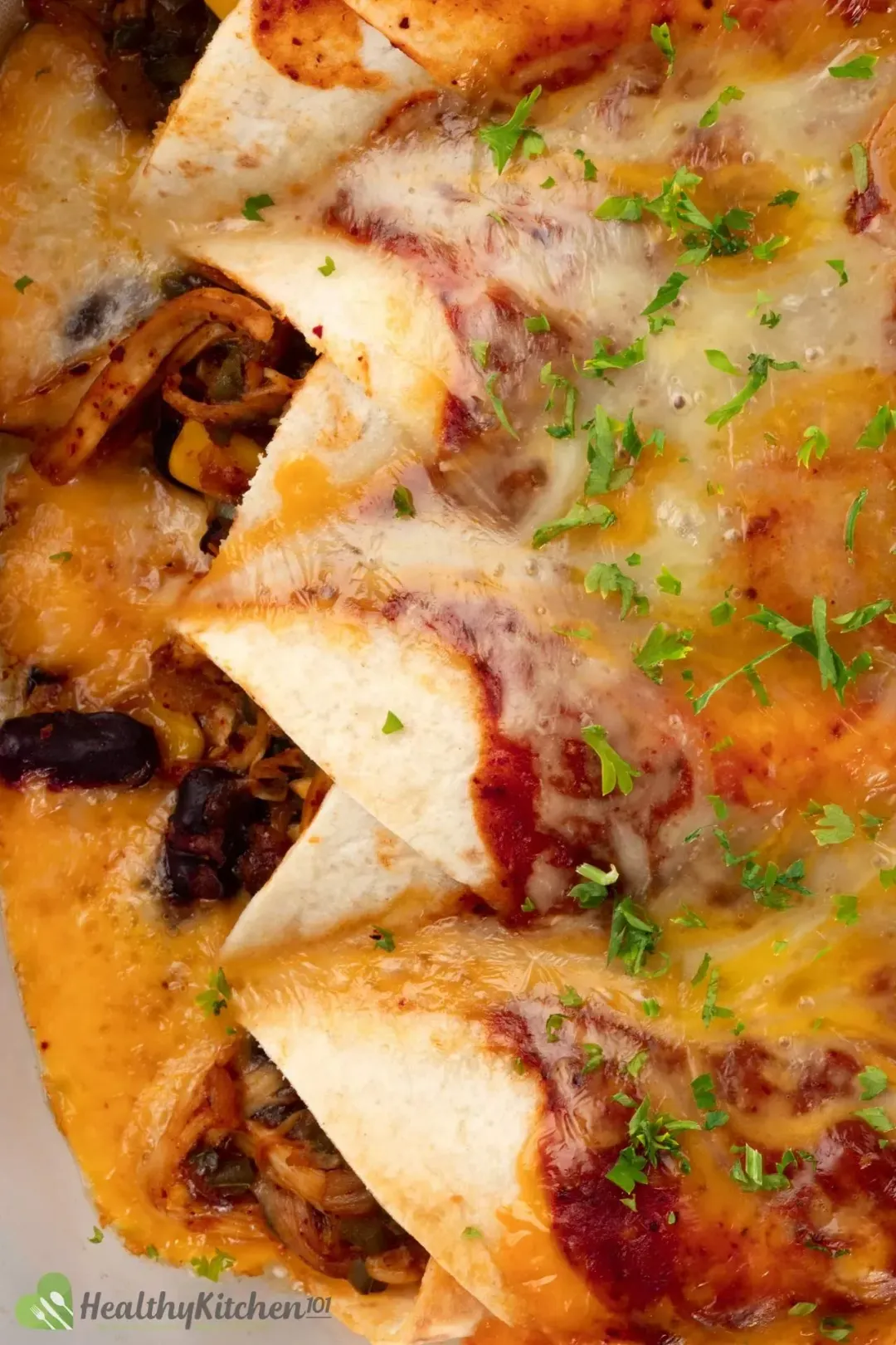 A close-up shot of four enchilada rolls topped with tomato sauce, melted cheddar cheese, and sprinkled with chopped parsley