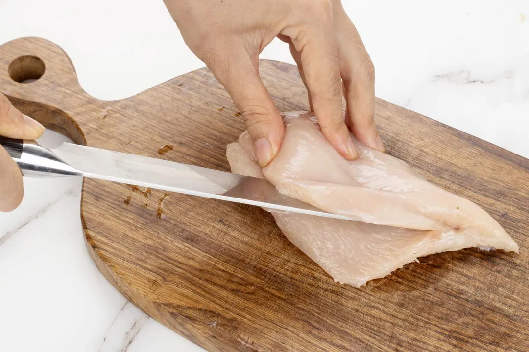 cutting chicken breast on a cutting board