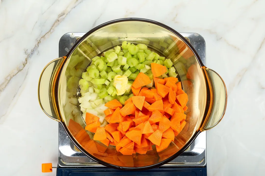 chopped celery carrots butter cooking in a glass pot