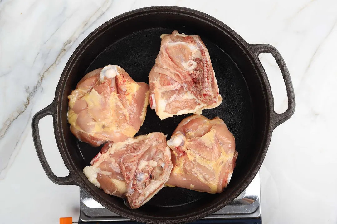 four chicken thighs in a cast iron skillet