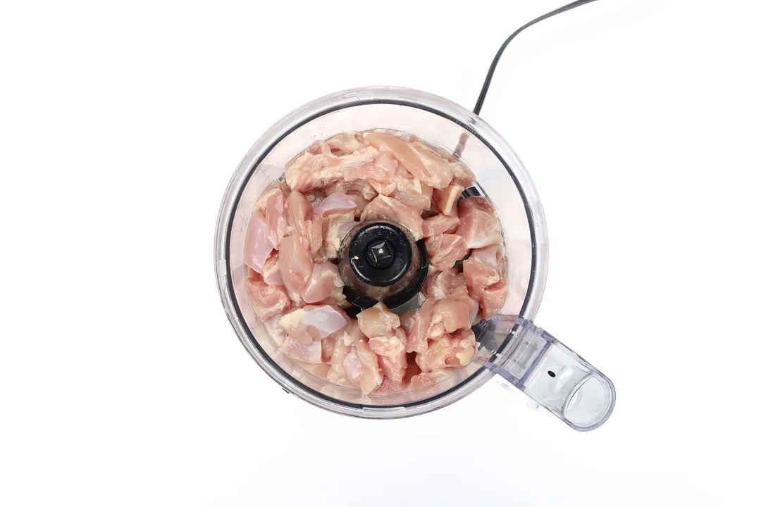 top view of slices chicken in a food processor