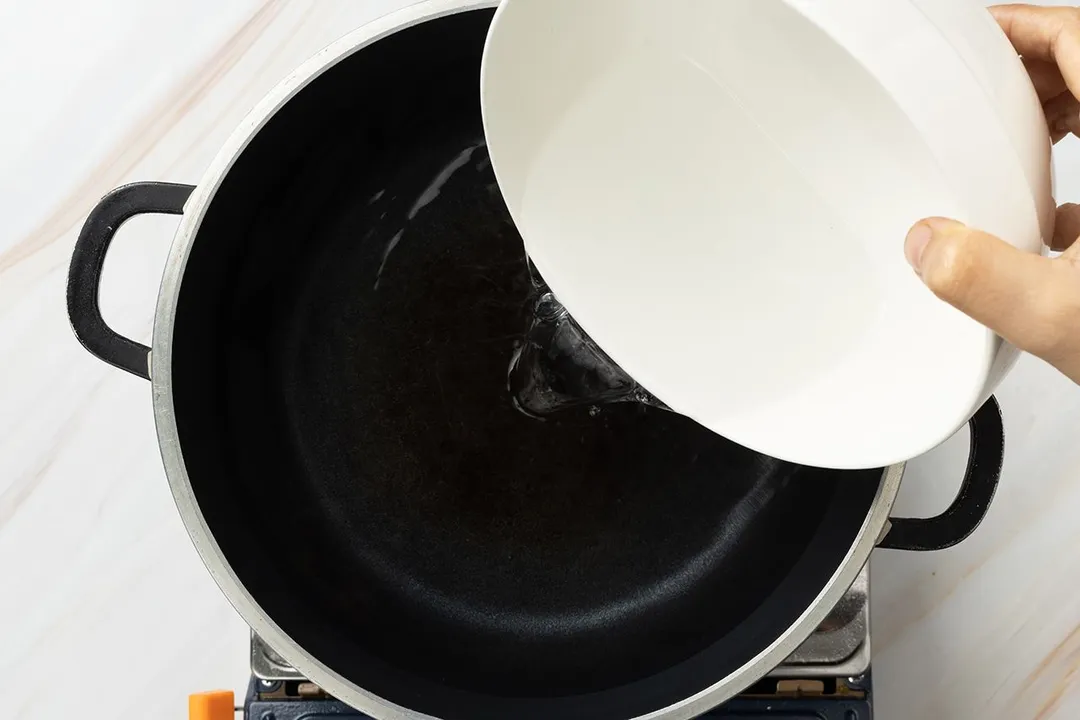 pouring water from a bowl to a pot