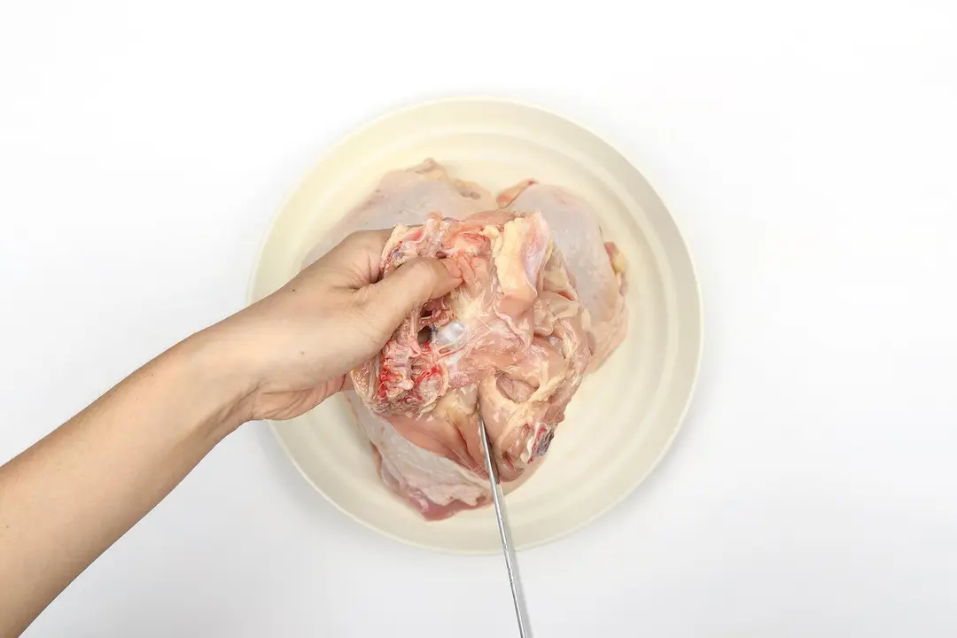 Chicken thighs being deboned with a knife