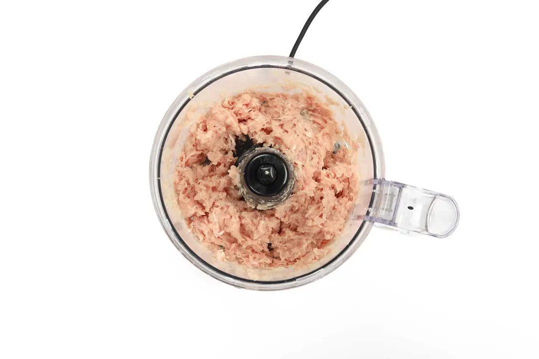 A food processor with ground meat inside it