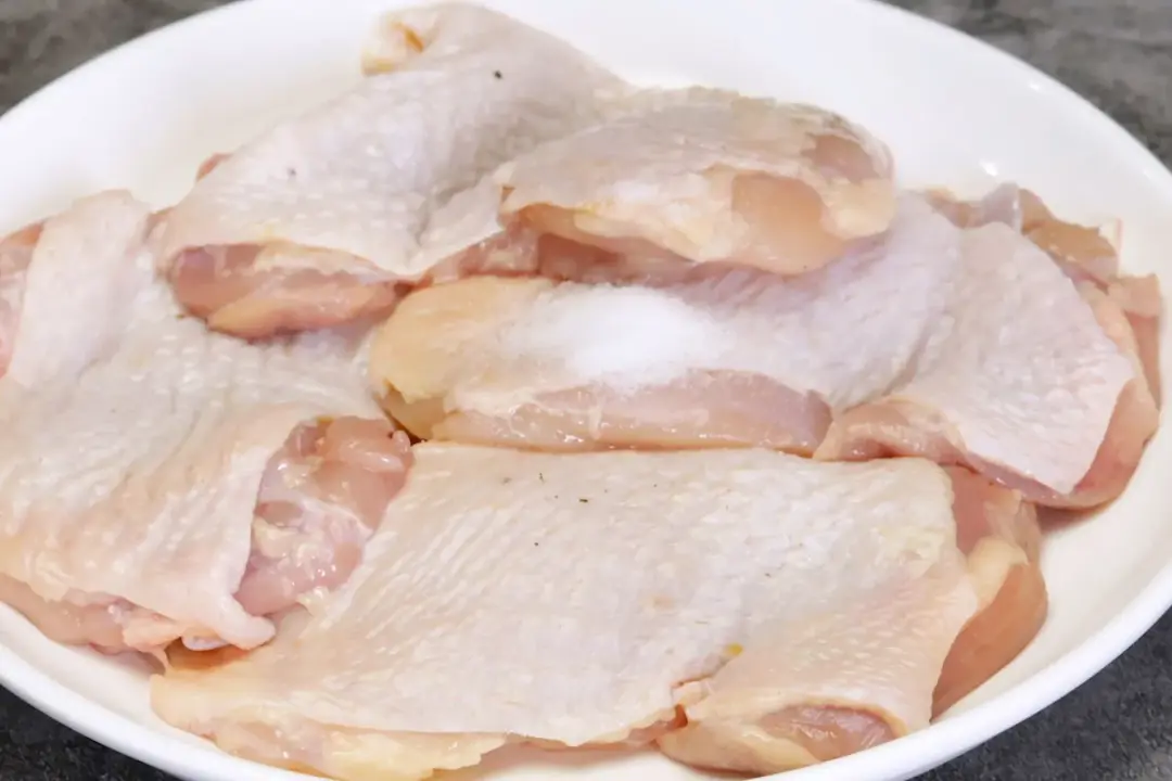 Raw deboned chicken thighs in a white plate