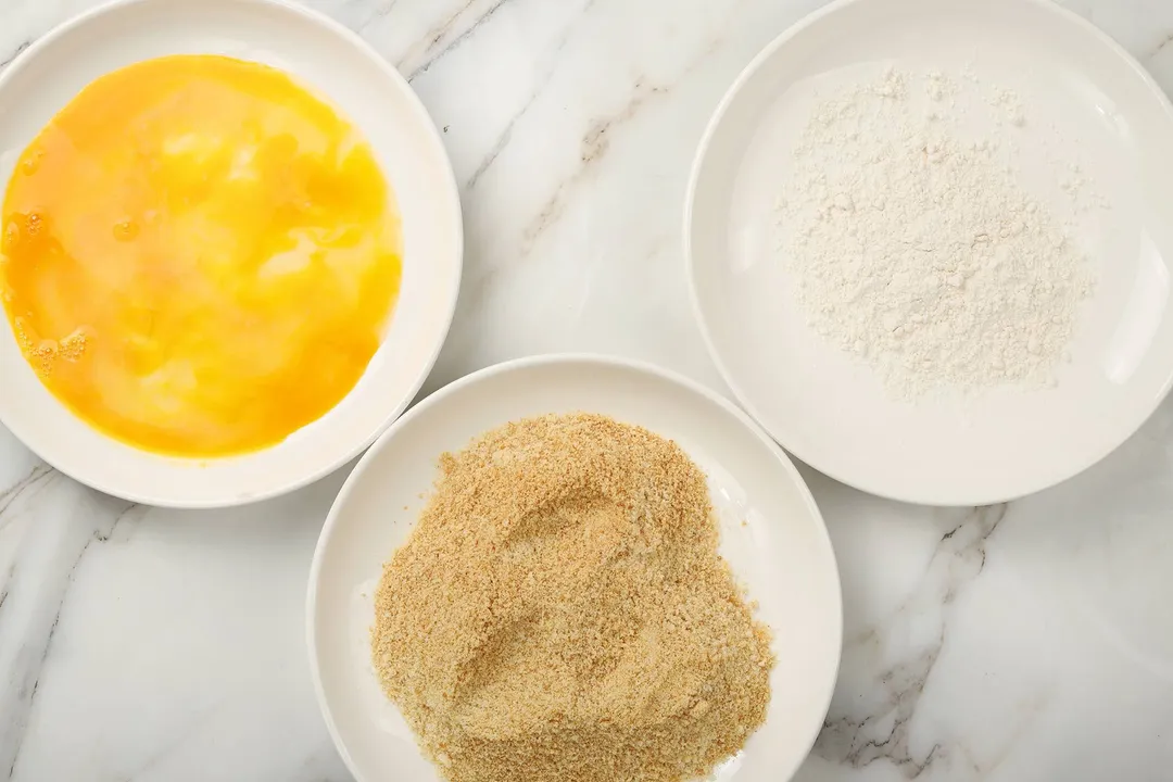 three plate on a plate: beaten egg, flour, breadcrumbs