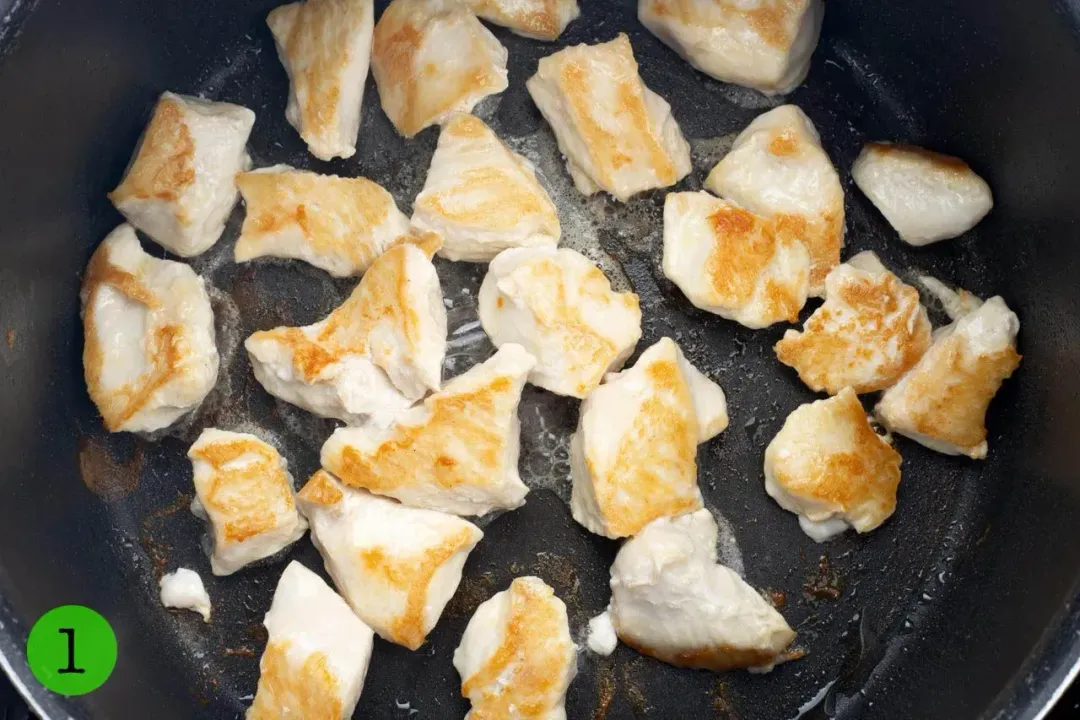 A pot cooking small cubes of chicken